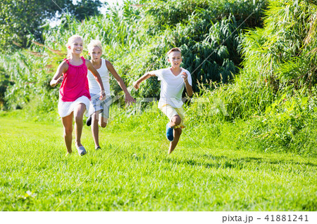 Group of laughing children having fun together outdoors running Group of laughing children having fun together outdoors running 41881241