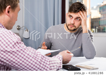 Man with friend looking worriedly at papers at home table Man with friend looking worriedly at papers at home table 41881286