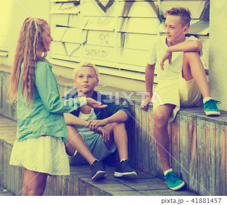Smiling girl with boys discussing outdoors 41881457
