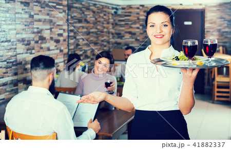 Pretty waitress greeting customers at table Pretty waitress greeting customers at table 41882337