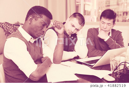 Three seriouse men are working with project and talking about documents together Three seriouse men are working with project and talking about documents together 41882519