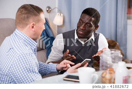 Happy African conversing with man at home using phone Happy African conversing with man at home using phone 41882672