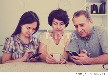 senior parents and daughter with smartphones . senior parents and daughter with smartphones . 41882731