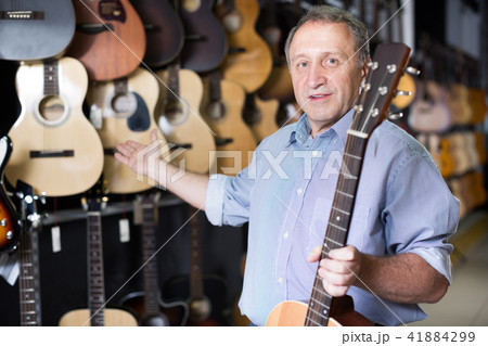 Smiling man musician buying new acoustic guitar 41884299
