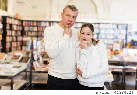 pensive man and preteen girl in bookstore pensive man and preteen girl in bookstore 41884523