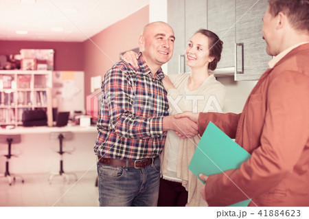 Smiling seller and spouses customers at kitchen furniture Smiling seller and spouses customers at kitchen furniture 41884623
