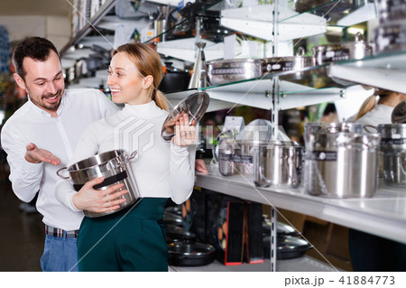 Young couple choosing new saucepan in dinnerware store Young couple choosing new saucepan in dinnerware store 41884773