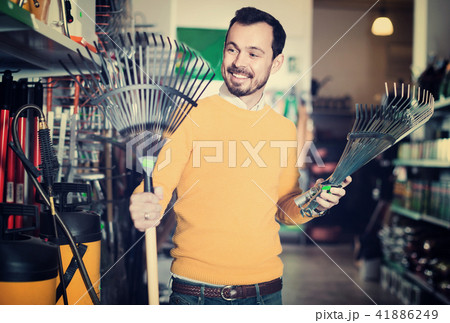 Man choosing various tools in garden equipment shop Man choosing various tools in garden equipment shop 41886249