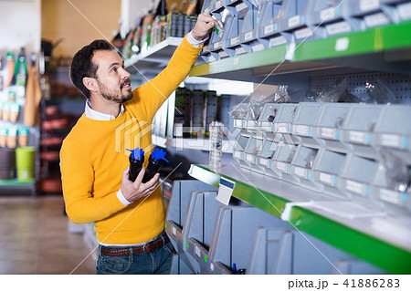 Man choosing various tools in garden equipment shop 41886283