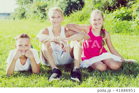 Girl with two friends resting on grass 41886951