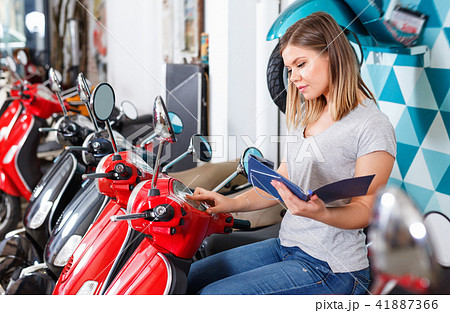 Smiling female is shopping and choosing new motobike in moto store. Smiling female is shopping and choosing new motobike in moto store. 41887366