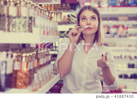 Stylish girl shopping in cosmetics store, choosing perfume 41887410