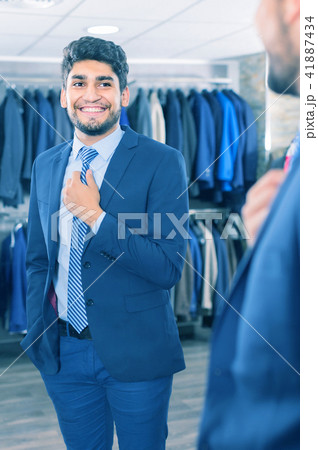 Smiling guy is trying on tie in front of the mirror 41887434