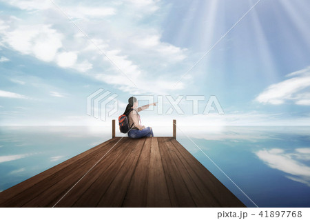 Young asian backpacker woman sitting and pointing Young asian backpacker woman sitting and pointing 41897768