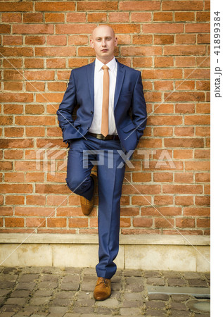 Young Fashionable Men In A Suit Against Brick Wallの写真素材