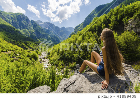 Woman sitting on a rock and looking at mountains Woman sitting on a rock and looking at mountains 41899409