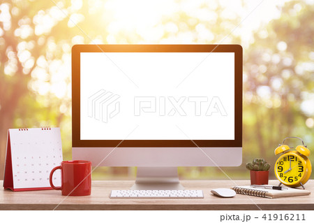 Modern desktop computer, Coffee cup, alarm clock, notebook and calendar on wooden table and abstract light blur and bokeh. Saved with clipping path. Work on nature and everywhere Concept 41916211
