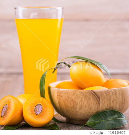 Fresh yellow marian plum fruit (Mayongchid in Thai name) and juice in glass on wooden table 41916402