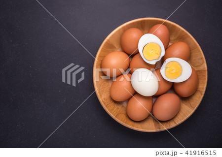 Fresh egg and boiled egg without shell. Top view on black stone 41916515