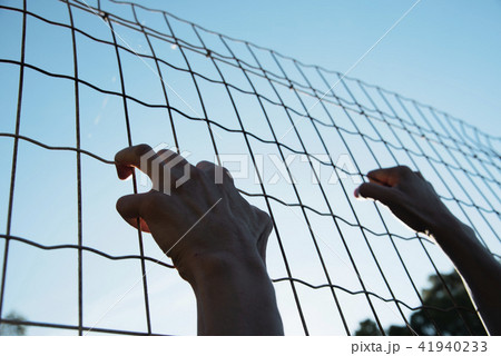 man climbing up a metal fence 41940233