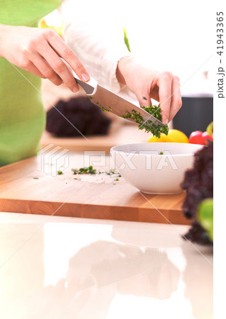 Close Up of human hands cooking vegetable salad in kitchen on the glass table with reflection 41943365