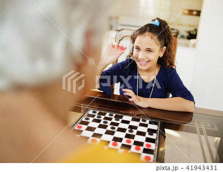 Grandma Playing Checkers Board Game With Granddaughter At Home 41943431
