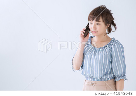 スマートフォンと女性 真顔 の写真素材