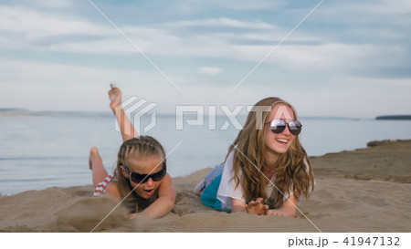 Two teenage children are sitting on the beach. 41947132