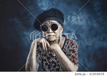 Cheerful nice old lady with kind smile looking at camera and posing  isolated over light green background. Yellow knitted sweatshirt. Happy old  age concept. Orange sunglasses. Friendly senior woman. Stock Photo |