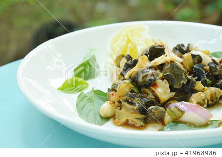 spicy golden apple snail with herb salad on plate 41968986