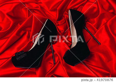 High-heeled shoes lying on red satin High-heeled shoes lying on red satin 41970876