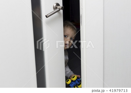 Cute toddler looking out from behind the ajar door 41979713