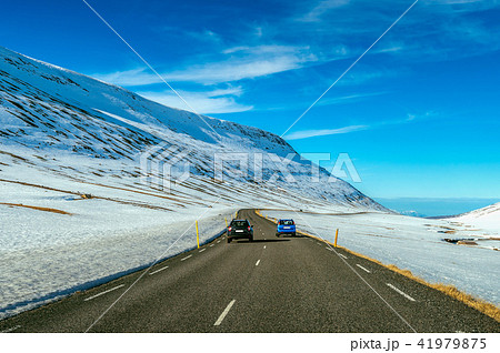 A long straight road and cars in winter. 41979875