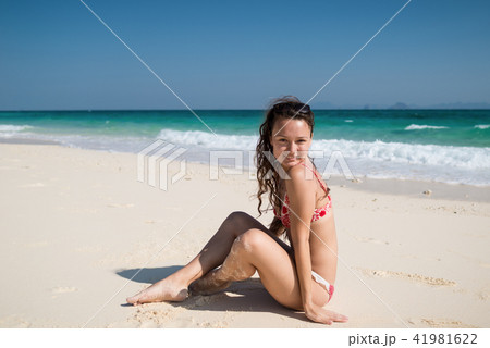 Young woman in swimwear sits on the beach on the coast of the ocean 41981622