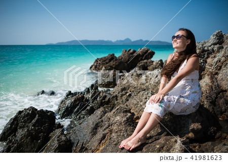 Young woman in dress sits on the rock on the coast of the ocean 41981623
