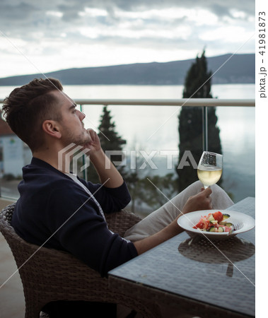 Pensive young man with glass of white wine Pensive young man with glass of white wine 41981873