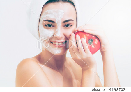 Woman get facial mask with tomato cream extract. Woman get facial mask with tomato cream extract. 41987024