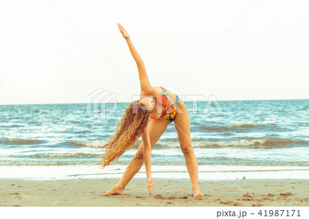 Young woman practices yoga on the beach in summer. 41987171