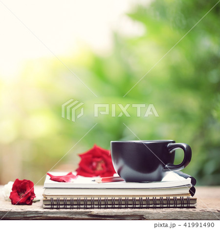 Black cup and notebook diary on wooden table Black cup and notebook diary on wooden table 41991490