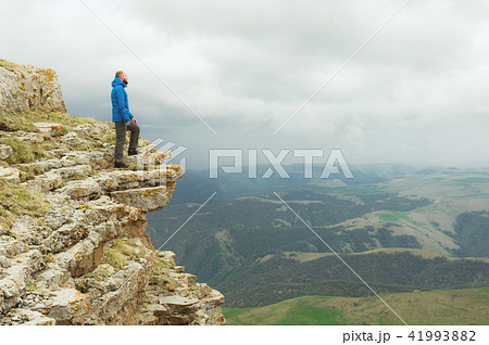 bearded hipster tourist man standing on the edge of a rock and looking out into the distance on an bearded hipster tourist man standing on the edge of a rock and looking out into the distance on an 41993882