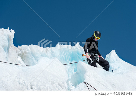 A professional mountaineer in a helmet and ski mask on the insurance does notch the ice ax in the 41993948