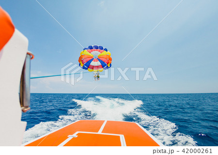 People flying on a colorful parachute towed by a motor boat People flying on a colorful parachute towed by a motor boat 42000261