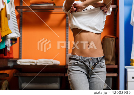 Young woman take off her t-shirt in wardrobe. 42002989