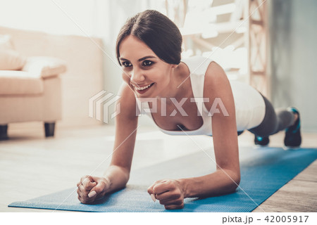 Young Smiling Woman Doing Exercises on Mat at Home Young Smiling Woman Doing Exercises on Mat at Home 42005917
