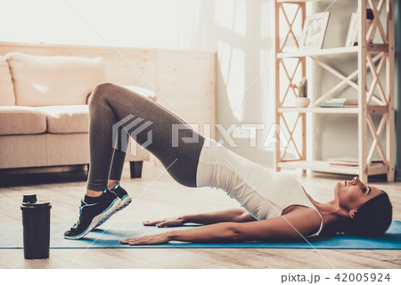Young Smiling Woman Doing Exercises on Mat at Home Young Smiling Woman Doing Exercises on Mat at Home 42005924