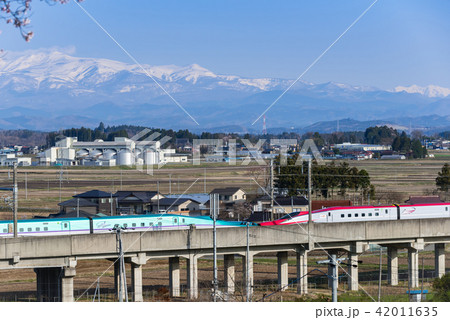 残雪の栗駒山と東北新幹線はやぶさとこまちの連結疾走の写真素材 