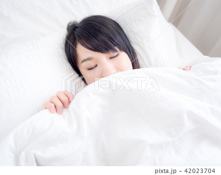 girl covers her face with white blanket in morning 42023704