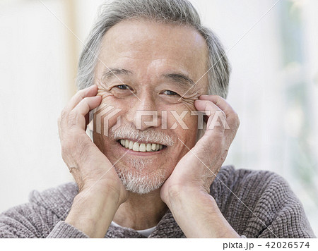 頬杖をついて微笑むシニア男性の写真素材