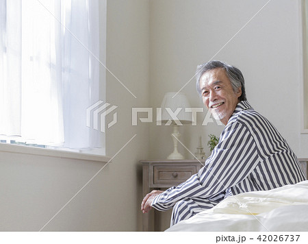 ベッドに座って振り返るシニア男性 42026737