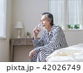 ベッドに座って水を飲むシニア男性 42026749